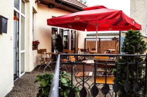 een patio met een rode parasol en tafels en stoelen bij Restaurace A Penzion Garnet in Olomouc