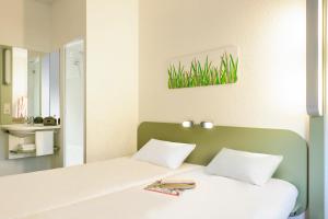 um quarto com uma cama branca e uma cabeceira verde em ibis budget Berlin Alexanderplatz em Berlim