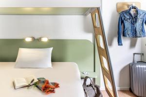 a bed sitting next to a dresser and a lamp at ibis budget Berlin Alexanderplatz in Berlin