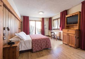 una camera d'albergo con un letto e una televisione di Limone Palace Aparthotel a Limone Piemonte