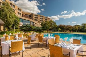 a restaurant with tables and chairs next to a pool at Avani Lesotho Hotel & Casino in Maseru