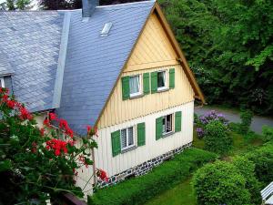 una casa gialla e verde con finestre e fiori verdi di Landhaus Wölfel a Bad Steben