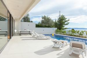 a swimming pool with white chairs and a swimming pool at Villa Sima in Makarska