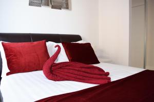 um cisne vermelho deitado numa cama com almofadas vermelhas em Contemporary Apartments, Balcony & Parking em Basingstoke