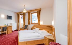 a bedroom with two beds and a desk at B&B Hotel Alpenrose Rooms & Apartments in Valles