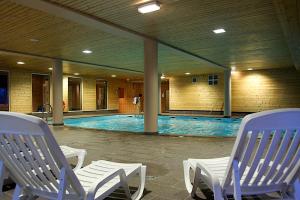 a swimming pool with two chairs and a swimming pool at Village Vacances Le Grépillon in Les Rousses