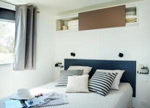 a small bedroom with a bed with striped pillows at Campeggio Ai Colli Fioriti in Castiglione dʼIntelvi