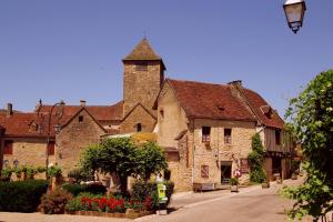 an old stone building with a tower on a street at Le Lac Bleu in Lacapelle-Marival