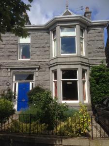 uma grande casa de pedra com uma porta azul em Denmore Guest House em Aberdeen
