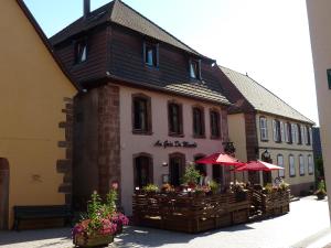 a building with tables and umbrellas in front of it at Les appartements d'estelle in La Petite-Pierre