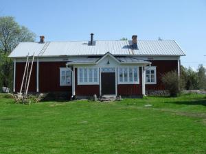 una casa roja con un campo verde delante de ella en Old Farmhouse Wanha Tupa, en Kristinestad