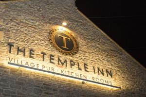 a sign on the side of a brick building with a clock at The Temple Inn in Temple Cloud