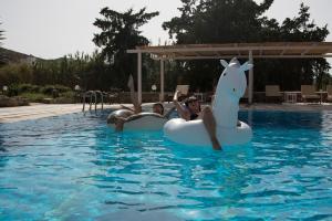 伊奧斯喬拉的住宿－Armadoros Hotel / Ios Backpackers，两个人在游泳池里乘充气垫子
