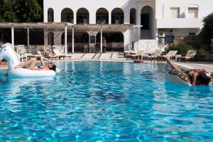 two people and a dog are in the swimming pool at Armadoros Hotel / Ios Backpackers in Ios Chora