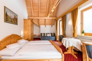 a bedroom with two beds and a table at B&B Hotel Alpenrose Rooms & Apartments in Valles