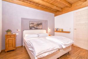 アルコにあるSweet Laghel Apartmentsの白いベッドと木製の天井が備わるベッドルーム1室が備わります。
