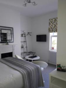 1 dormitorio con cama, chimenea y espejo en Coast B&B, en Bexhill-on-Sea