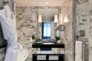 uma casa de banho com um lavatório, uma banheira e um espelho. em Hôtel San Régis em Paris