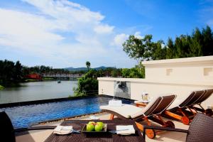 a patio with chairs and a swimming pool at Dusit Thani Laguna Phuket in Bang Tao Beach