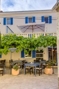 eine Terrasse mit Tischen und einem Sonnenschirm vor einem Gebäude in der Unterkunft Hotel Sansegus in Susak