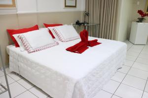 ein großes weißes Bett mit einem roten Bogen drauf in der Unterkunft Canadá Hotel in Rio Verde