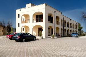 zwei Autos, die vor einem weißen Gebäude geparkt sind in der Unterkunft Hotel Salento in Specchia