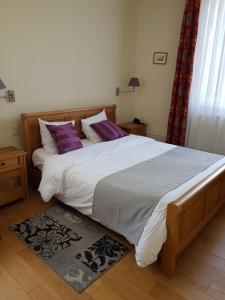 - une chambre dotée d'un grand lit avec des draps blancs et des oreillers violets dans l'établissement LOGIS - Château de la Motte - Hôtel & Restaurant, à Liessies