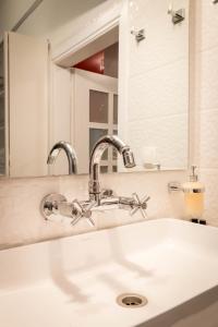 a bathroom sink with two faucets and a mirror at Martin’s Akropolis loft in Athens