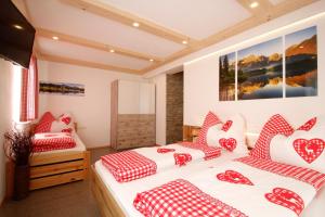 Cette chambre comprend 2 lits avec des oreillers rouges et blancs. dans l'établissement Appartement Almzeit mit Infrarotkabine, à Großsölk