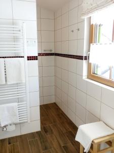 ein Bad mit weiß gefliesten Wänden und einer Dusche in der Unterkunft Gästehaus Attenhauser in Unterammergau