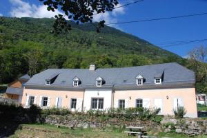 una gran casa blanca con una montaña en el fondo en Les Gîtes du Pla de Moura, en Luz-Saint-Sauveur