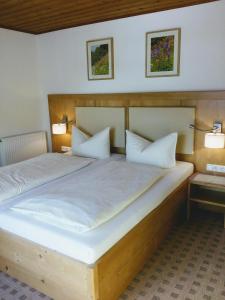 a bedroom with a large wooden bed with two pillows at Gästehaus Attenhauser in Unterammergau