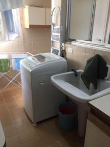 a bathroom with a sink and a washing machine at Apartamento Guaruja Pitangueiras in Guarujá