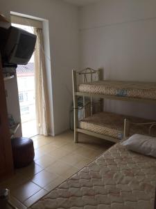 a bedroom with two bunk beds and a television at Apartamento Guaruja Pitangueiras in Guarujá