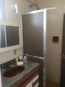 a bathroom with a sink and a shower with a mirror at Apartamento Guaruja Pitangueiras in Guarujá