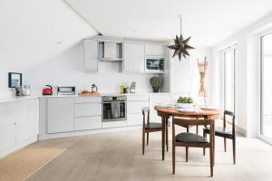 ロンドンにあるNew and Modern House for 6 Batterseaの白いキッチン(木製テーブル、椅子付)