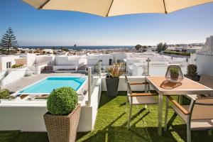 een balkon met een tafel en stoelen en een zwembad bij Flower Beach Suite 23 in Playa Honda