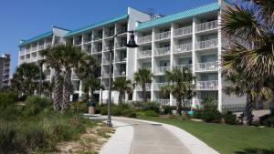 a large white building with palm trees in front of it at Bermuda Sands On The Boardwalk in Myrtle Beach