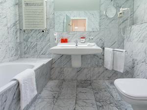 
a bathroom with a sink, toilet and bathtub at DORMERO Hotel Burghausen in Burghausen
