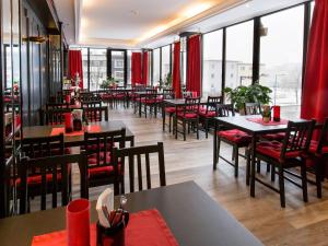 a restaurant with tables and chairs and windows at DORMERO Hotel Burghausen in Burghausen