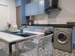 a kitchen with blue cabinets and a table and chairs at Apartamento 1ª linea by Hugo Beach Hotel - Familias in Gandía