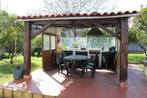 une pergola en bois avec une table et des chaises sur une terrasse dans l'établissement Casa de alojamento local (T2) Queluz de Baixo, à Oeiras