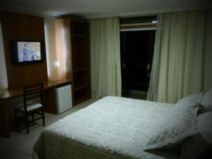 a bedroom with a bed and a chair and a television at Setiba Pousada Park in Guarapari +19 photos