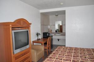 a bedroom with a television and a table and a kitchen at The Palace Inn in Oxnard