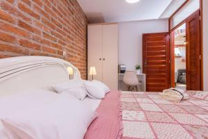 a bedroom with a bed with a brick wall at Apartments Rensi in Zadar
