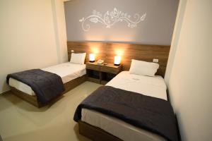 a bedroom with two beds and a table with two lamps at Hotel Escala in Chiclayo