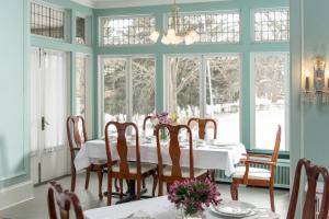 uma sala de jantar com mesa, cadeiras e janelas em Idlwilde Inn em Watkins Glen