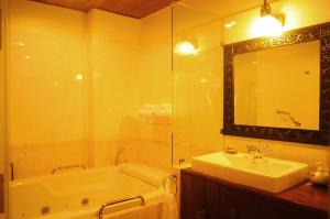 a bathroom with a sink, mirror, and bathtub at Ruenkanok Thaihouse Resort in Hua Hin