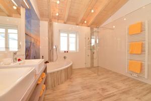 y baño con 2 lavabos, bañera y ducha. en Landhaus Harmonie, en Riezlern