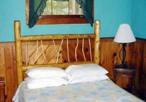 a bedroom with a wooden bed with two pillows at The Elms Waterfront Cottages in Lake Luzerne